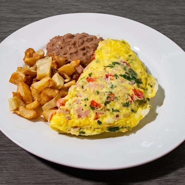 Breakfast plate with a colorful omelet, crispy home fries, and a side of refried beans.